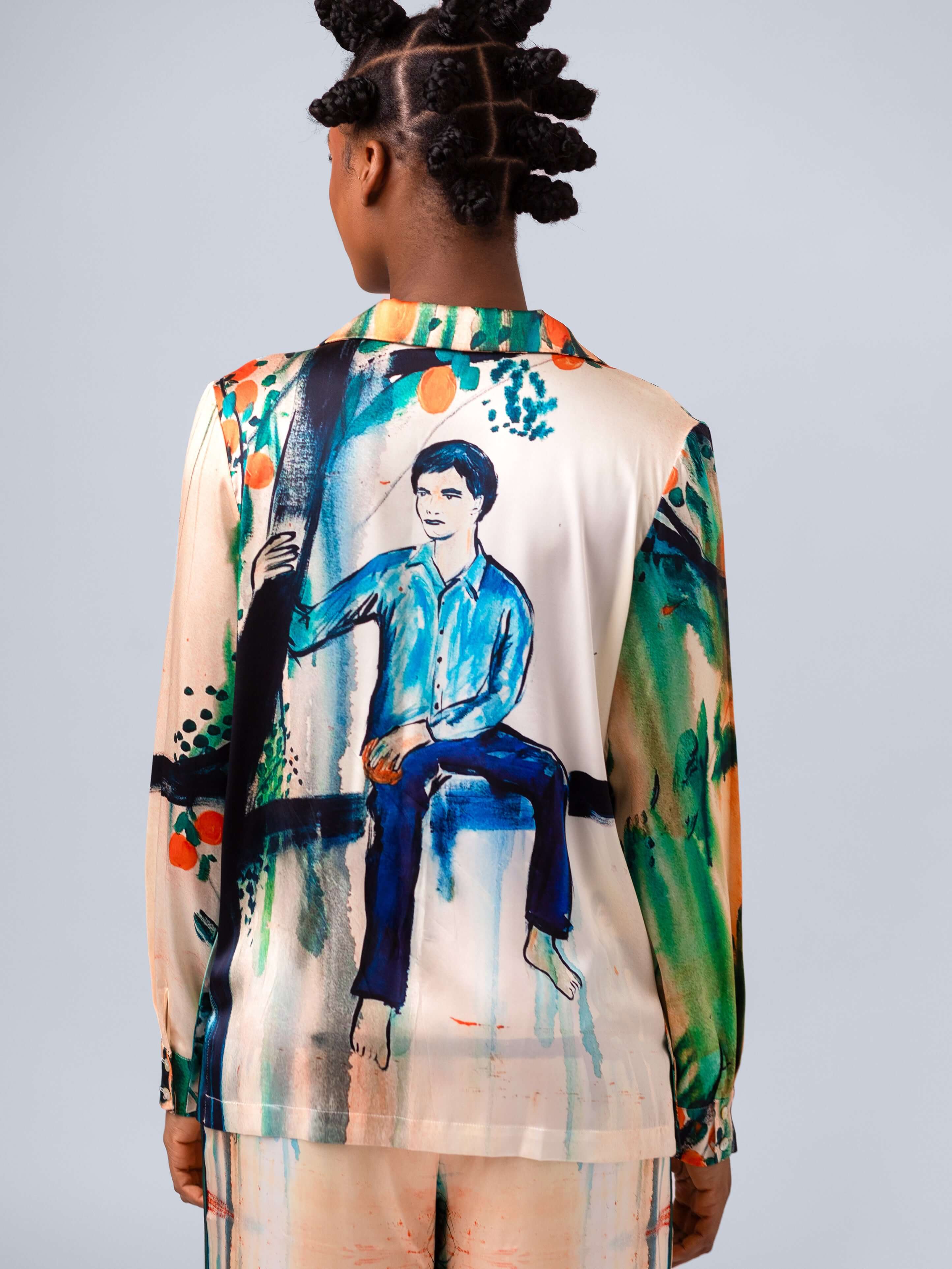 Back view of a model wearing a colorful shirt vest featuring a painting of a boy, part of the Les Orangers collection.